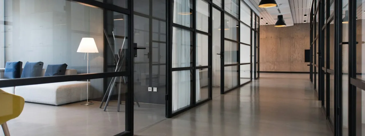 Oficina con puestos compartidos, grandes ventanas y plantas