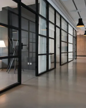 Oficina con puestos compartidos, grandes ventanas y plantas