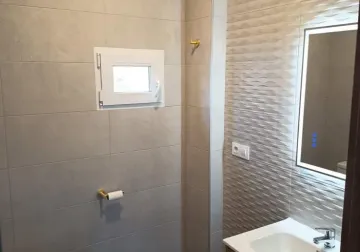 Baño con ducha, revestimiento claro y distribución compacta