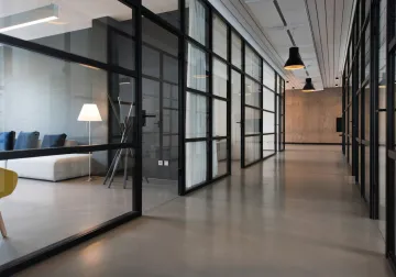 Oficina con puestos compartidos, grandes ventanas y plantas
